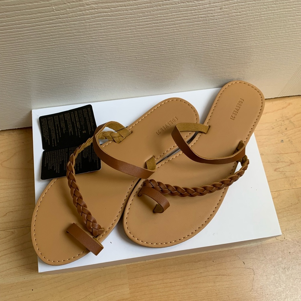 Flat tan sandals with a slender band and toe loop!